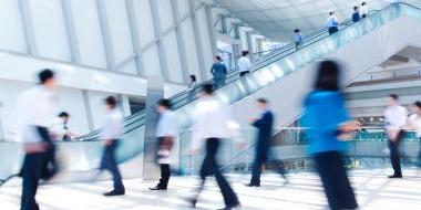 Blurred image of people in a building with escalators